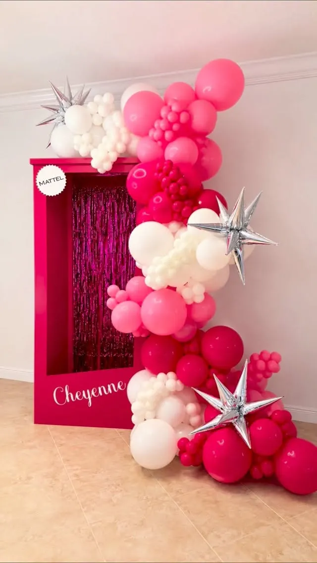 Hot pink and white balloon garland with silver stars on a life-size doll box frame