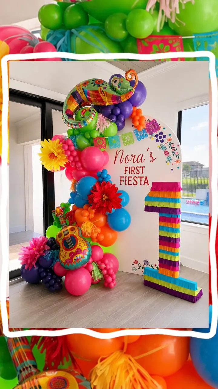 Bright multicolor balloon garland on an arched first birthday backdrop