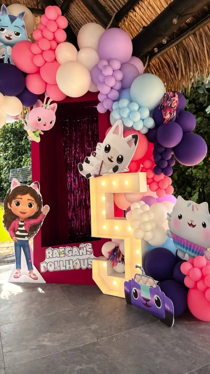 Pink and purple balloon garland around a photo frame with a light-up number five